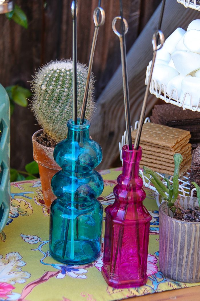 pink and blue glass jars holding metal skewers for a s'mores bar