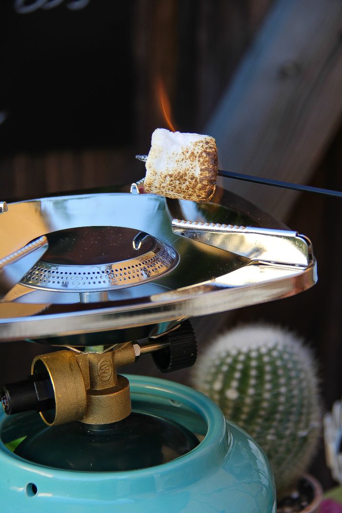 a marshmallow being toasted on a portable camp stove