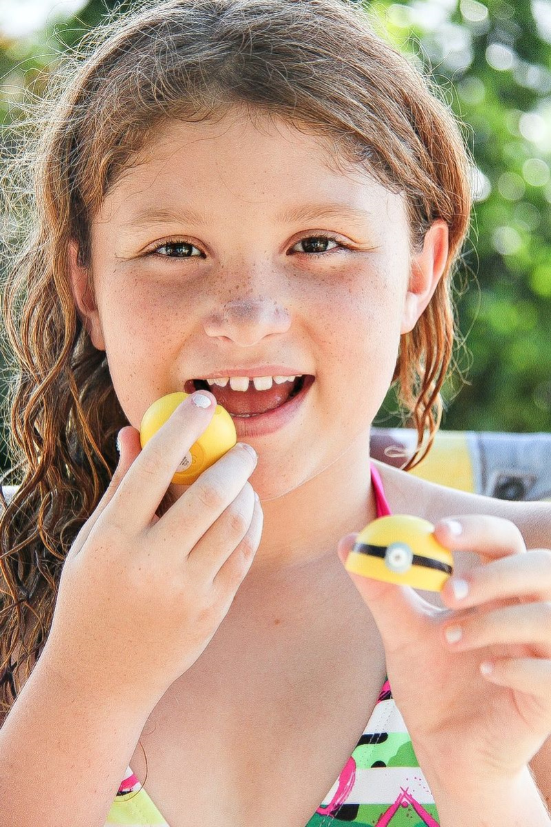 a girl using EOS yellow lip balm with a minion face drawn on it