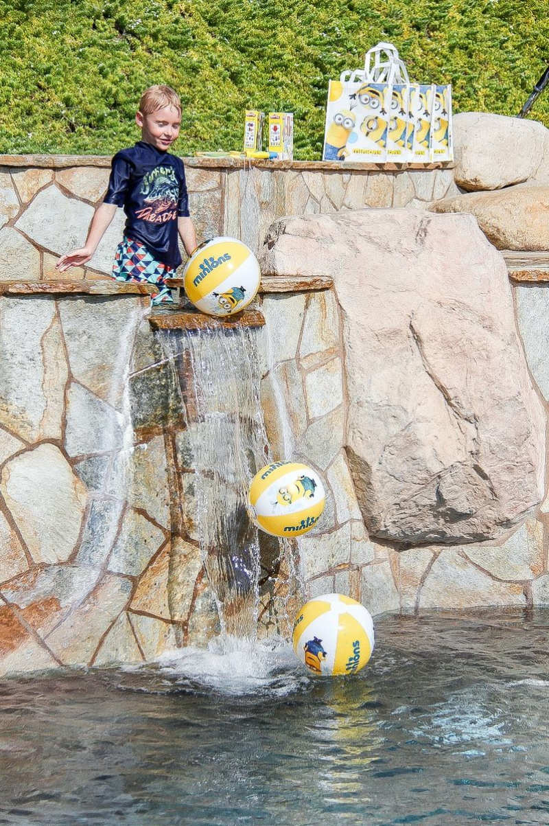 a boy putting minion beach balls over a waterfall