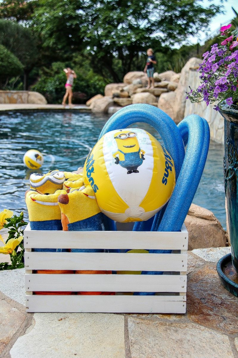 a white box filled with minion towels and pool tools with a pool in the background