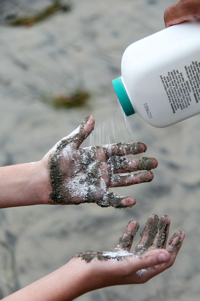 powder being sprinkled onto sand covered hands