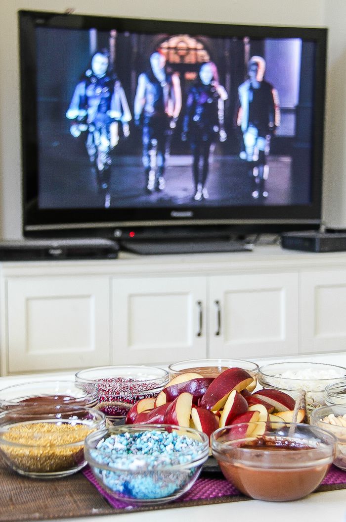 disney descendants playing on a television with apple slice movie night treats