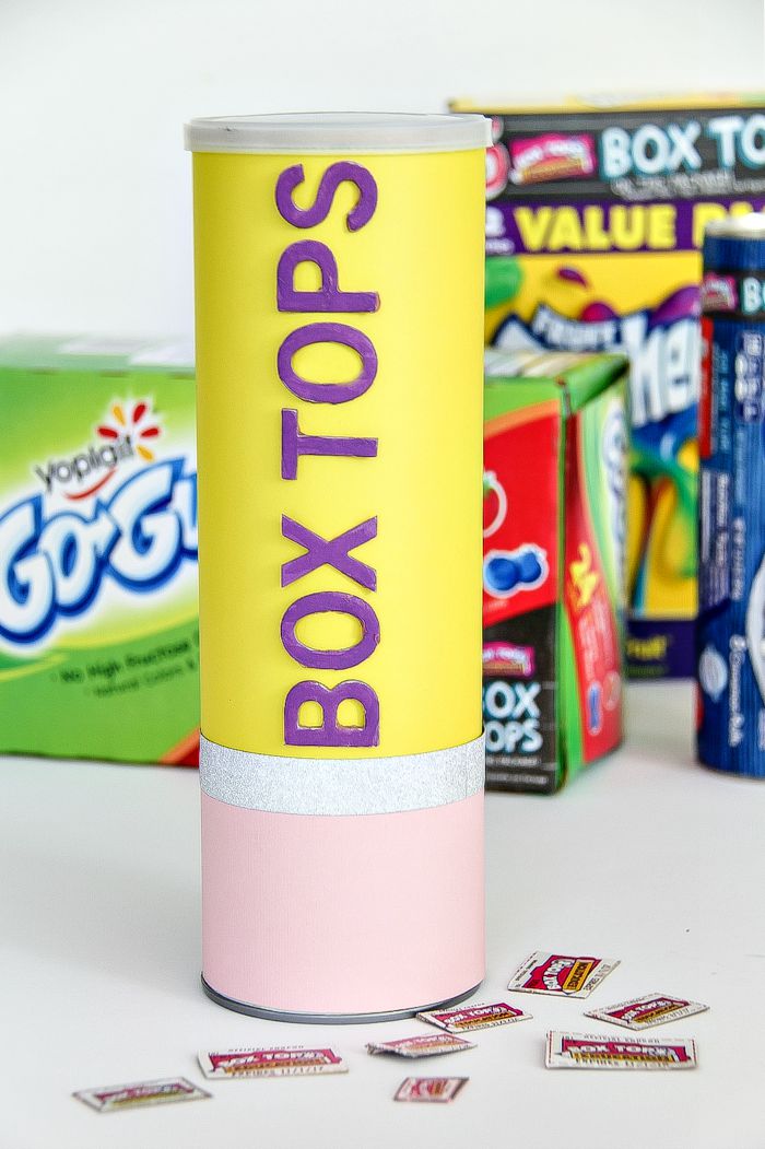 a box tops collection canister shaped like a pencil with products in the background that have box tops