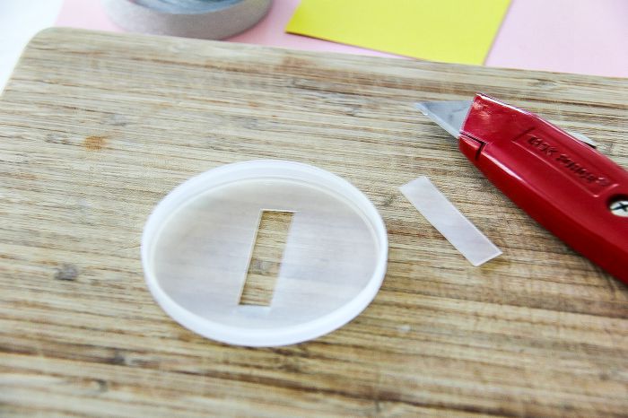 The plastic top of a pringles carton with a slot cut into it like a money box