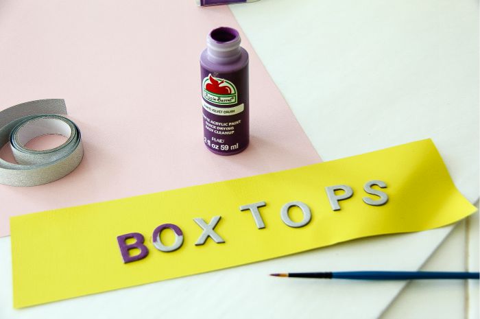 cardboard letters spelling box tops being painted