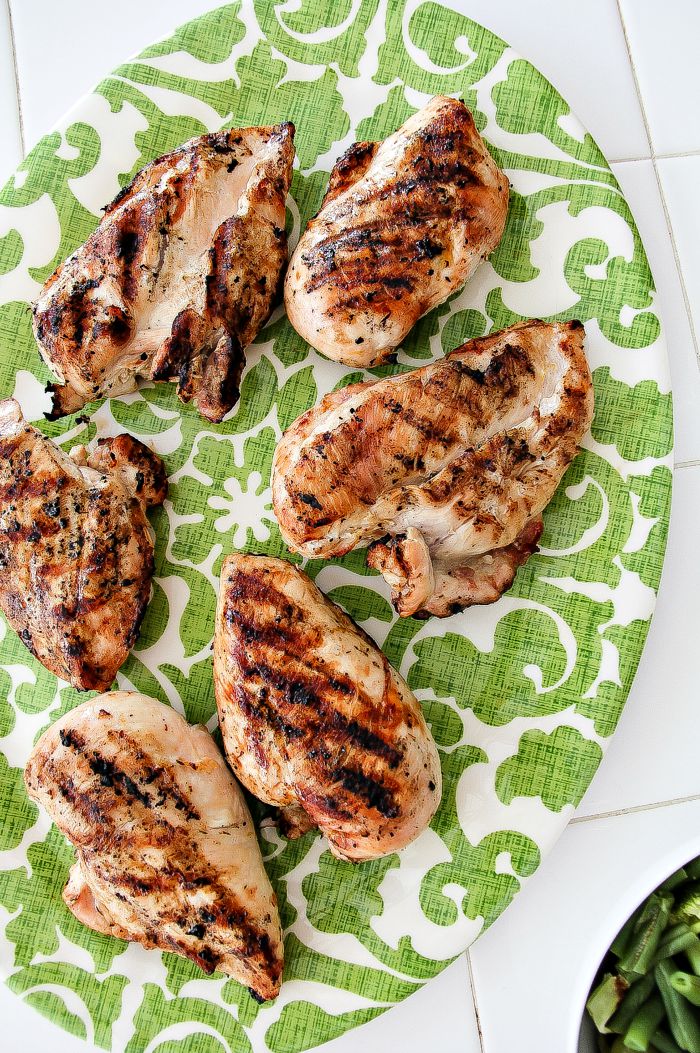 grilled lemon chicken breasts on a green and white serving tray