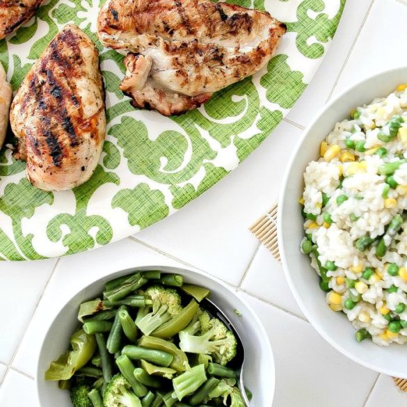 grilled chicken on a serving plate with risotto and steamed green vegetables