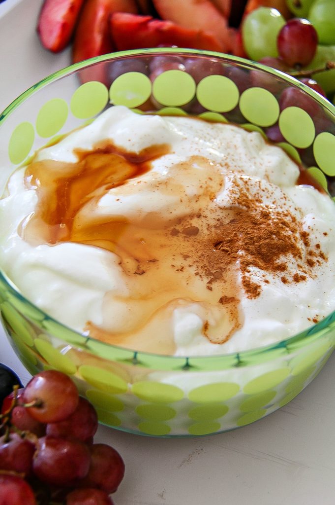 cinnamon honey and yogurt in a bowl surrounded by fresh fruit