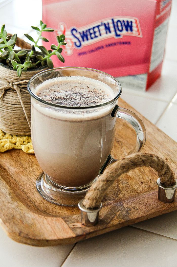 hot chocolate in a glass mug with a box of sweet 'n low