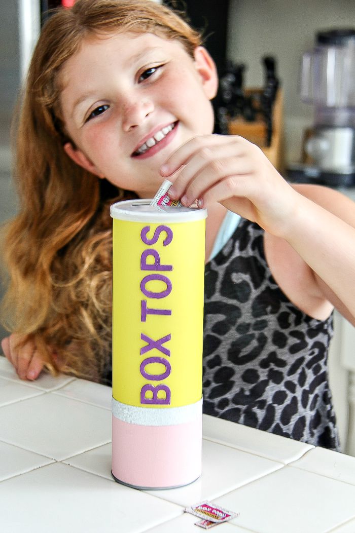 a girl putting box tops into a pencil box tops collection container