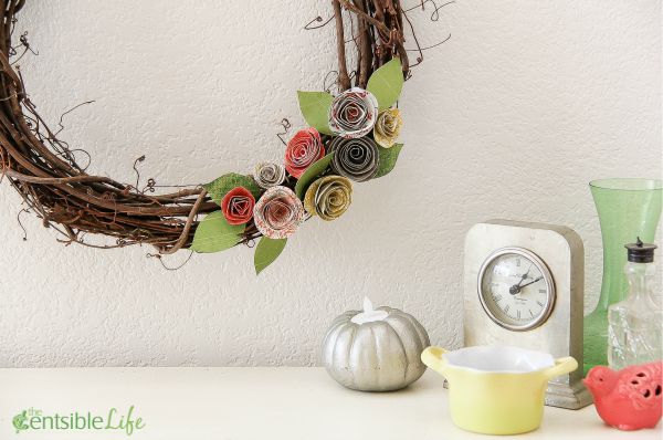a twig wreath with homemade paper flowers attached to it for fall.