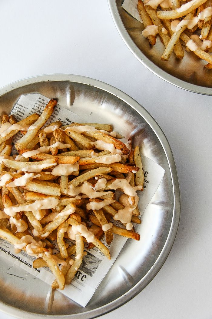 french fries on a silver tray covered in sriracha sauce