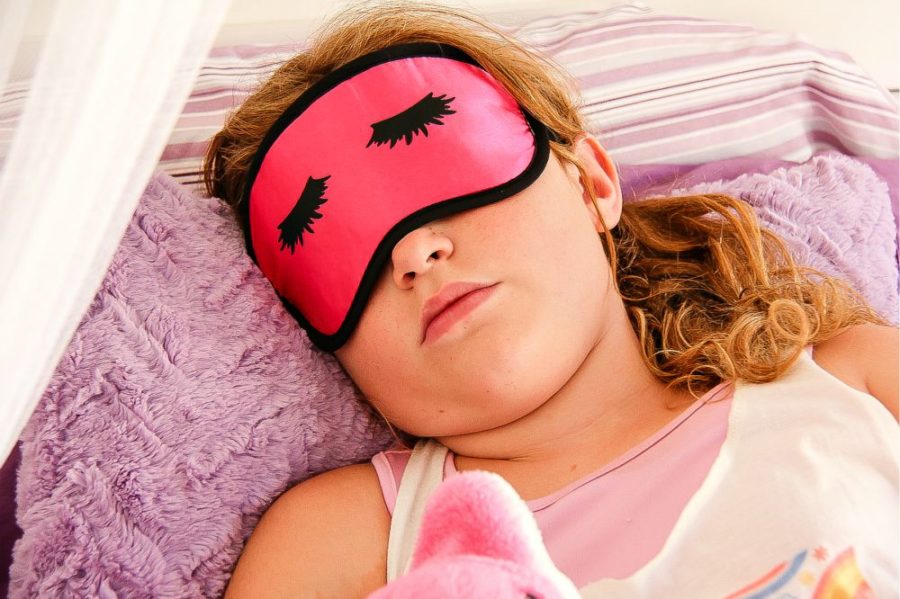 girl sleeping wearing a pink eye mask