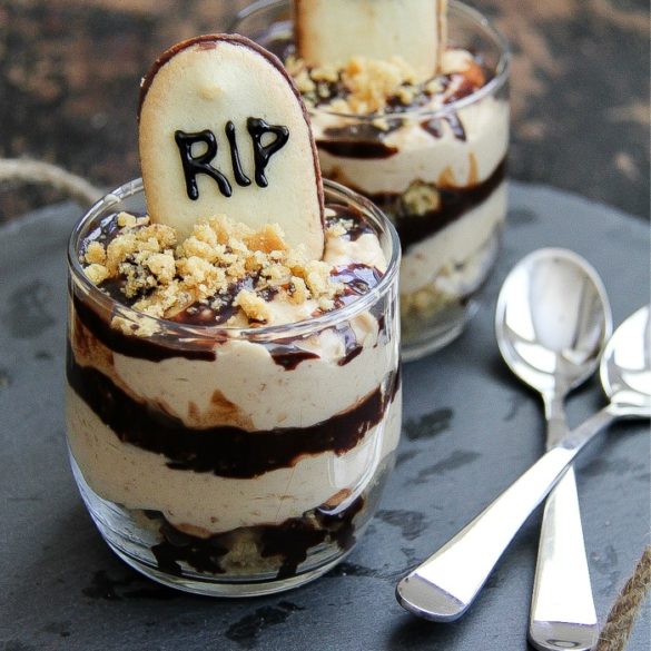 peanut butter and chocolate layered in glasses with a graveyard cookie in the top