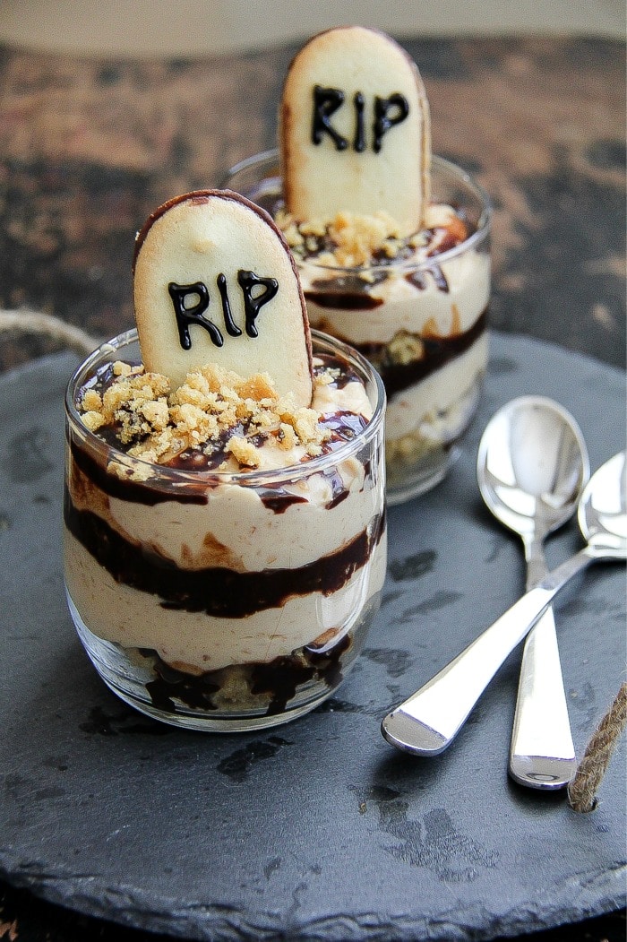 peanut butter and chocolate layered in glasses with a graveyard cookie in the top for a Halloween dessert