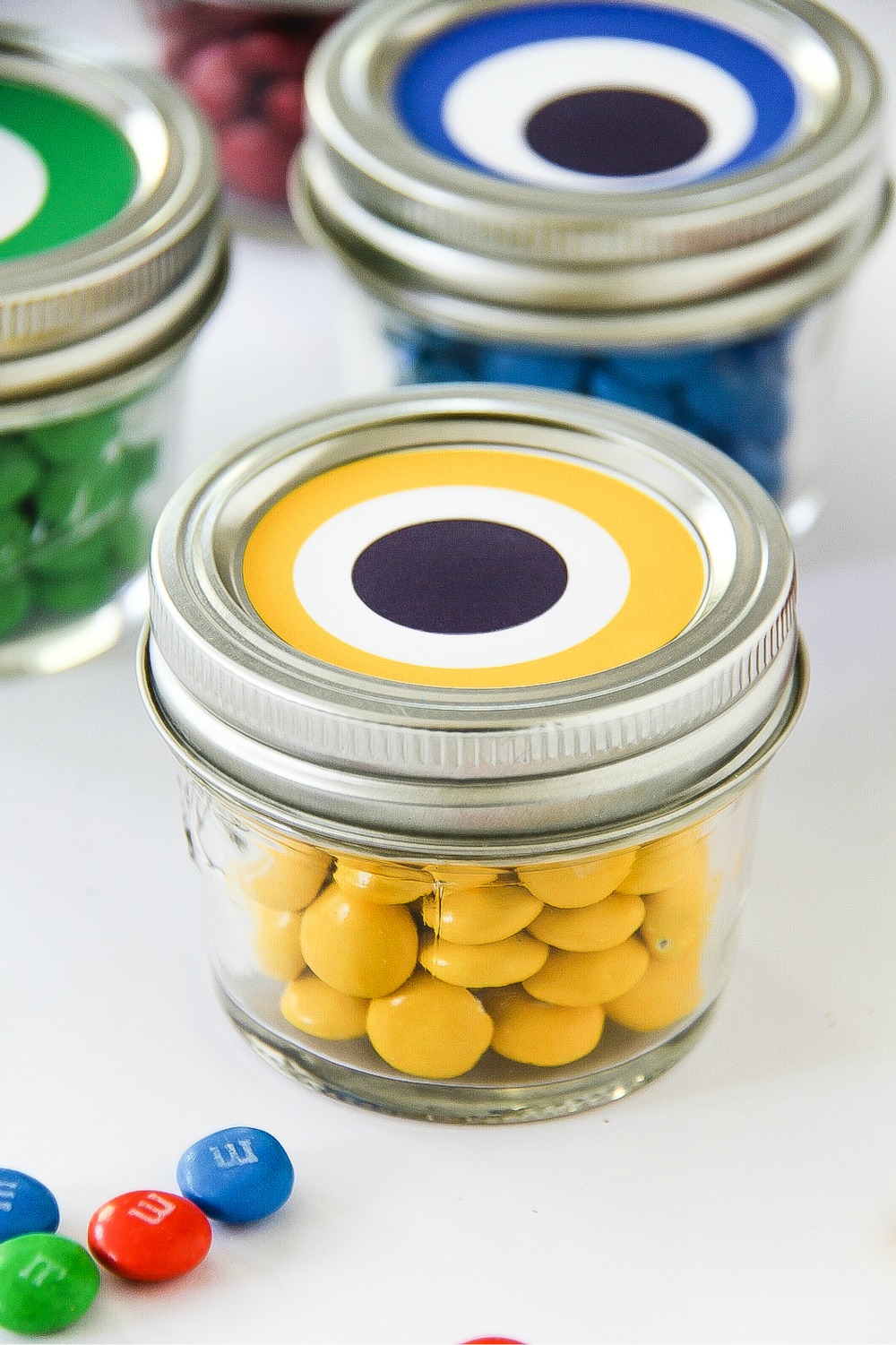 small canning jars with colorful candy and eyeballs on top to look like monsters