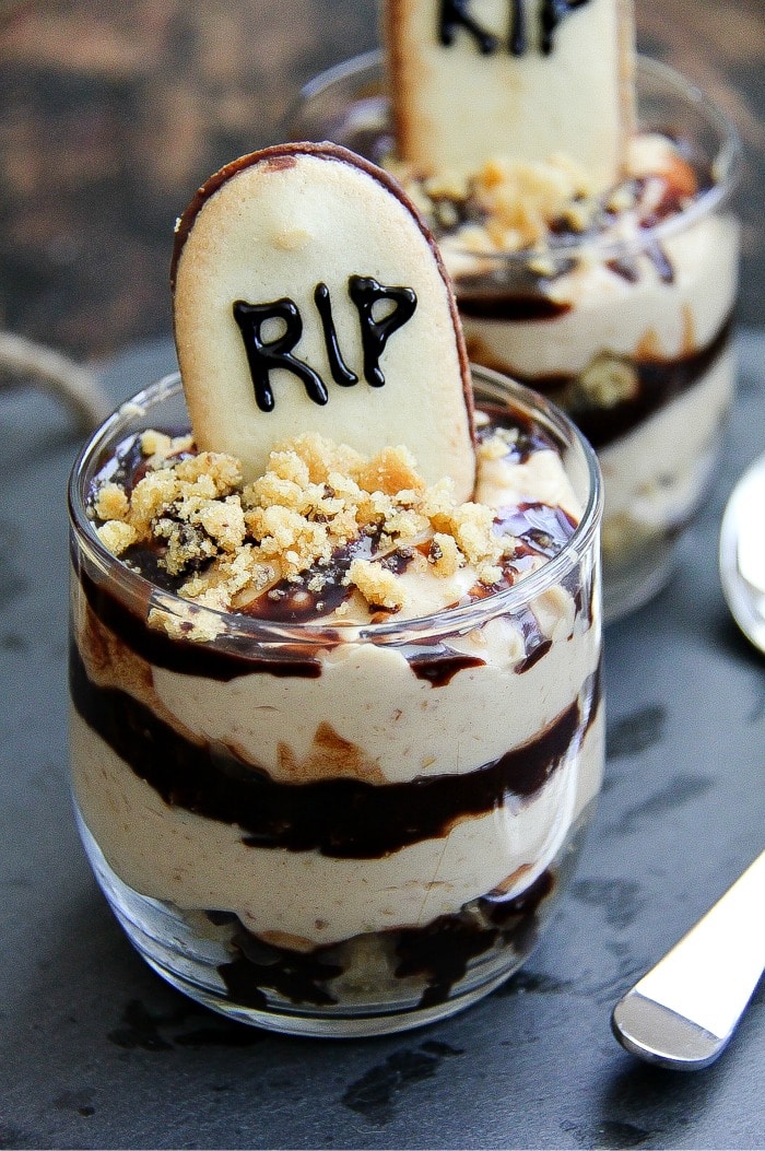 Halloween dessert with chocolate and peanut butter layered in a glass with a RIP graveyard cookie in the top