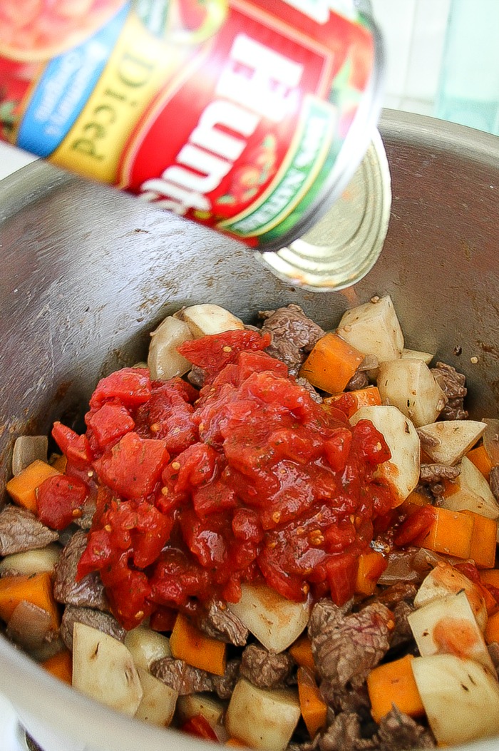 a can of tomatoes being tipped into a stew pot