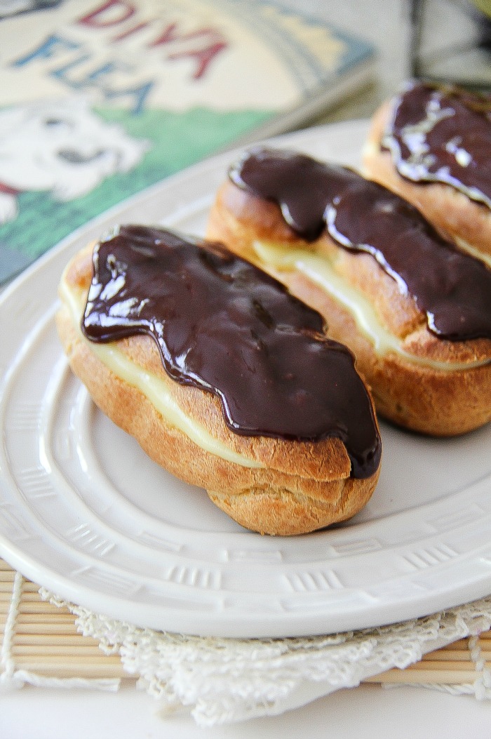 homemade chocolate and custard eclairs on a white tray