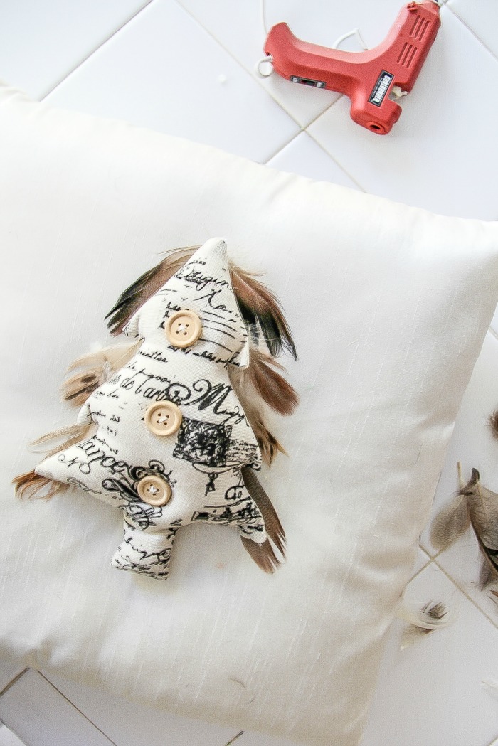 a fabric christmas tree being attached to a cushion with a glue gun