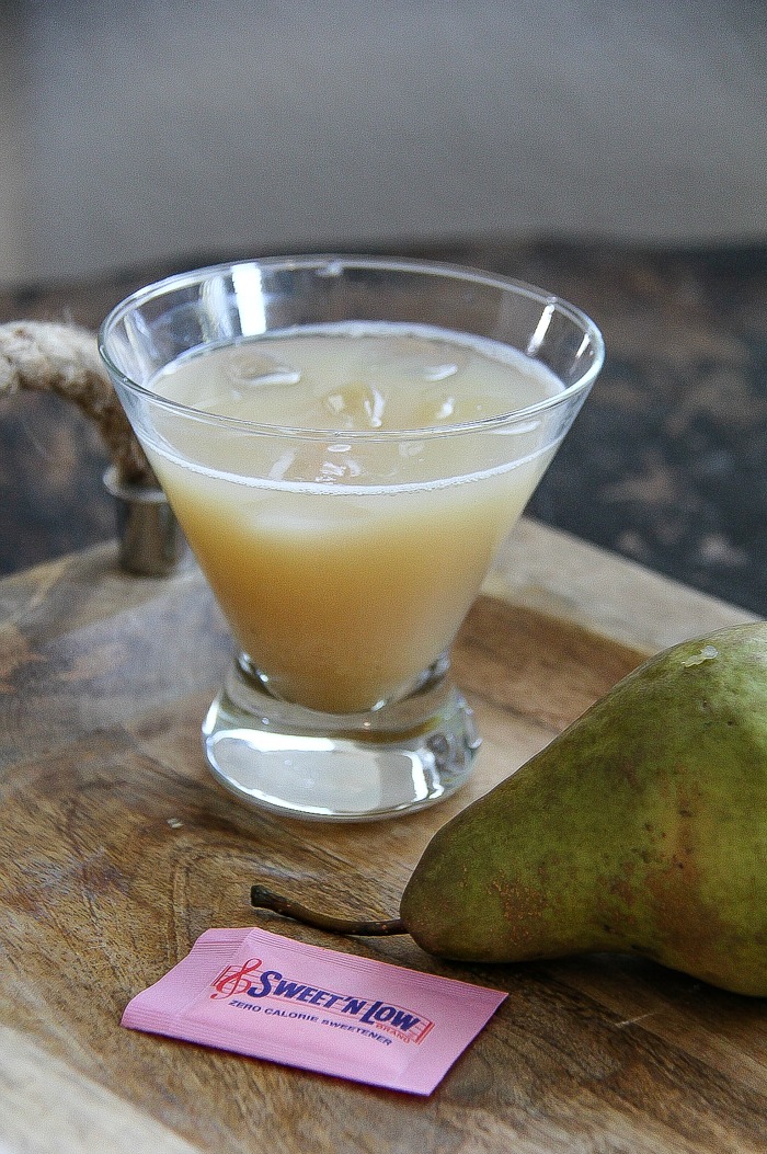 a pear caramel cocktail with a fresh pair and packet of sweet n low