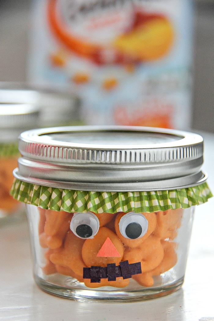 a fall treat jar turned into a scarecrow and filled with goldfish crackers