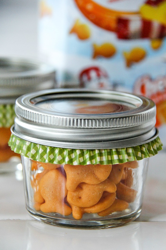 a canning jar filled with goldfish crackers and a green cupcake liner inside it