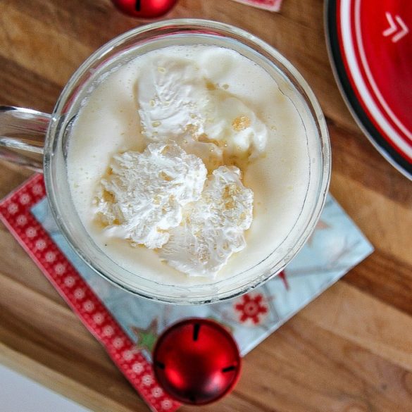 a white chocolate hot chocolate in a glass with red christmas ornaments