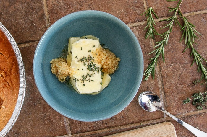 butter, garlic, rosemary, and thyme in a blue bowl