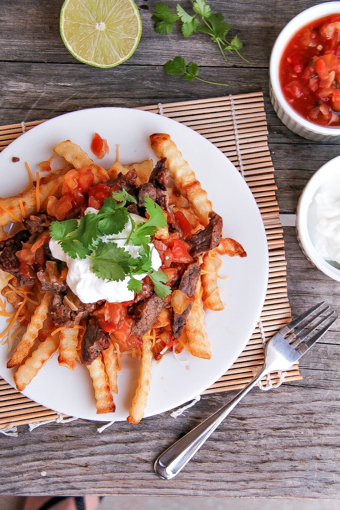 view from above of carne asada fries with lime, salsa and sour cream