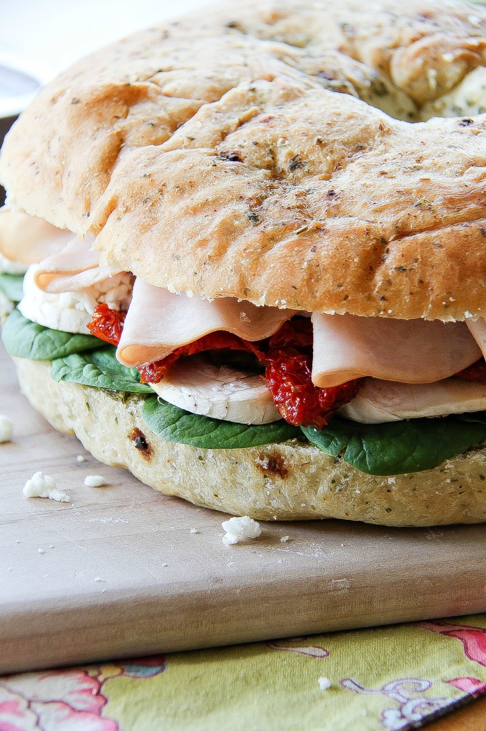 a focaccia sandwich filled with turkey, mushrooms, sundried tomatoes, and spinach