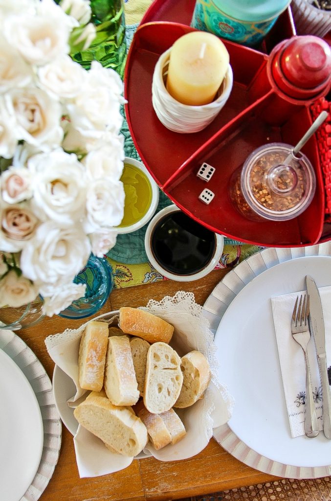 looking down on a dinner table with fresh cut bread and olive oil and balsamic dipping sauces