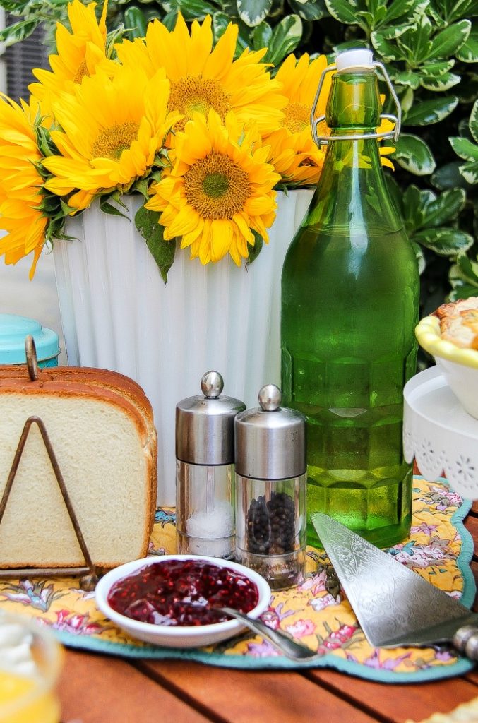 Raspberry jam and toast in a toast holder in front of fresh sunflowers in a vase