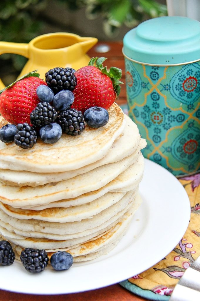 A stack of pancakes topped with fresh blueberries, blackberries, and strawberries.