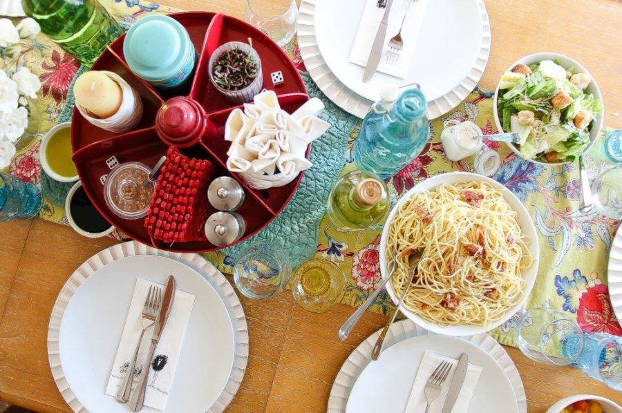 looking down over a dinner table of spaghetti carbonara and Caesar salad