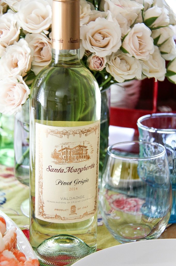a bottle of Santa Margherita Pinot Grigio with a glass and flowers in the background