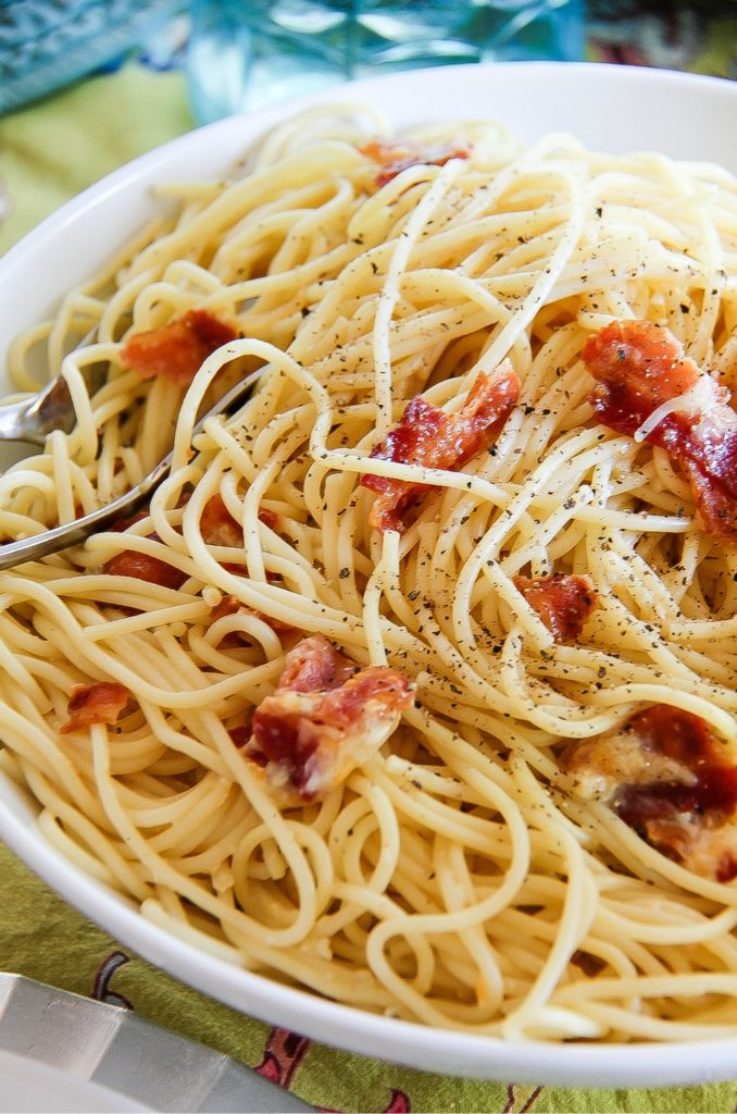 a serving bowl filled with spaghetti alla carbonara