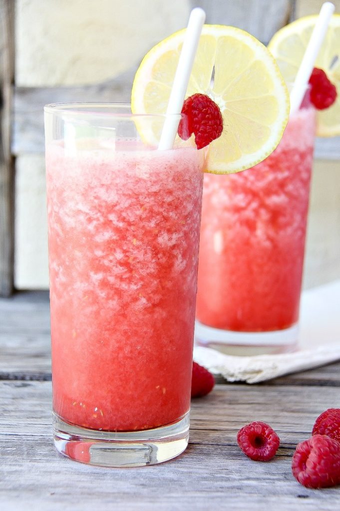 raspberry lemonade freeze in a glass garnished with fresh raspberries and lemon slices