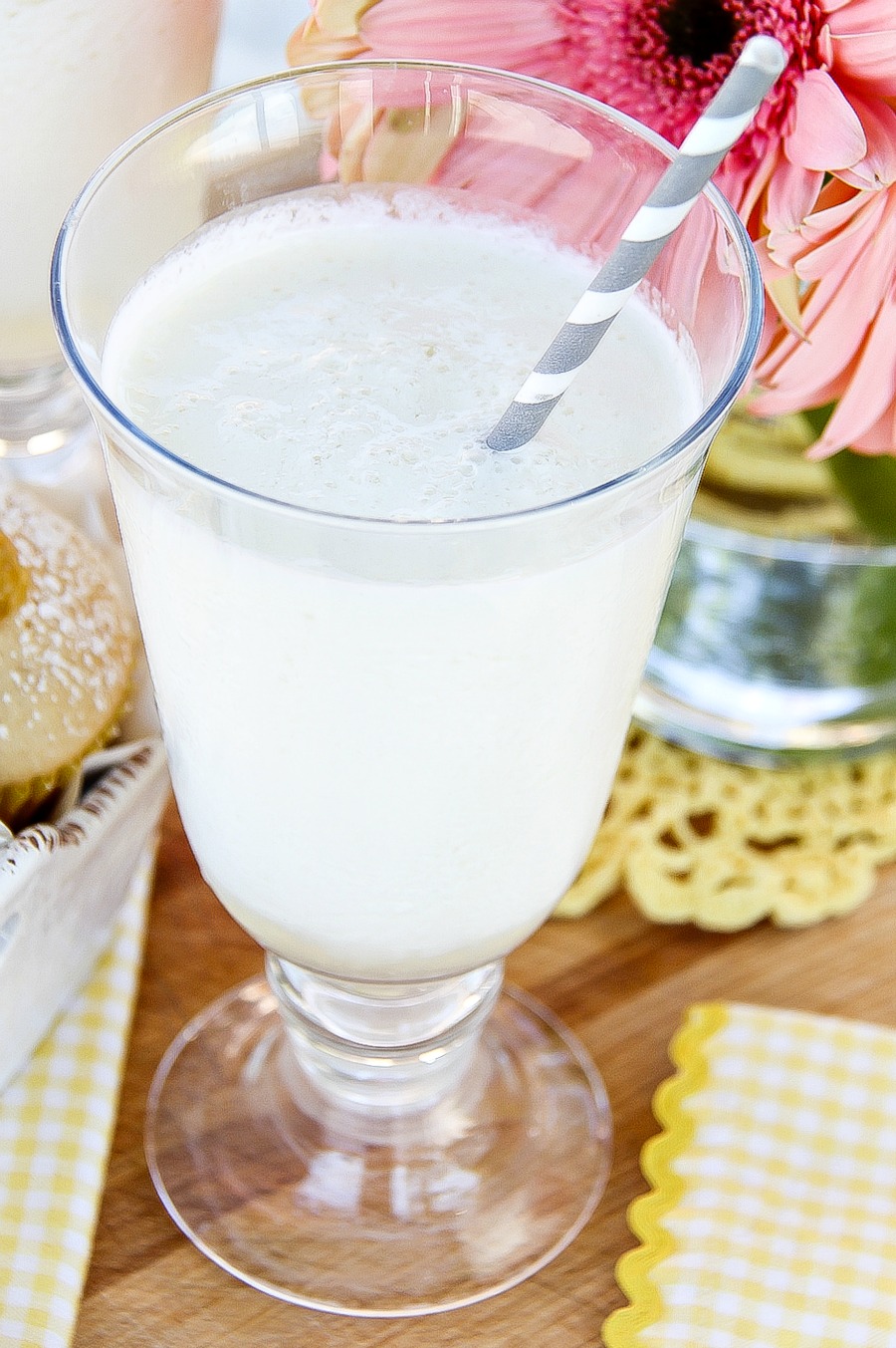 a lemonade milkshake in a glass with a grey and white paper straw