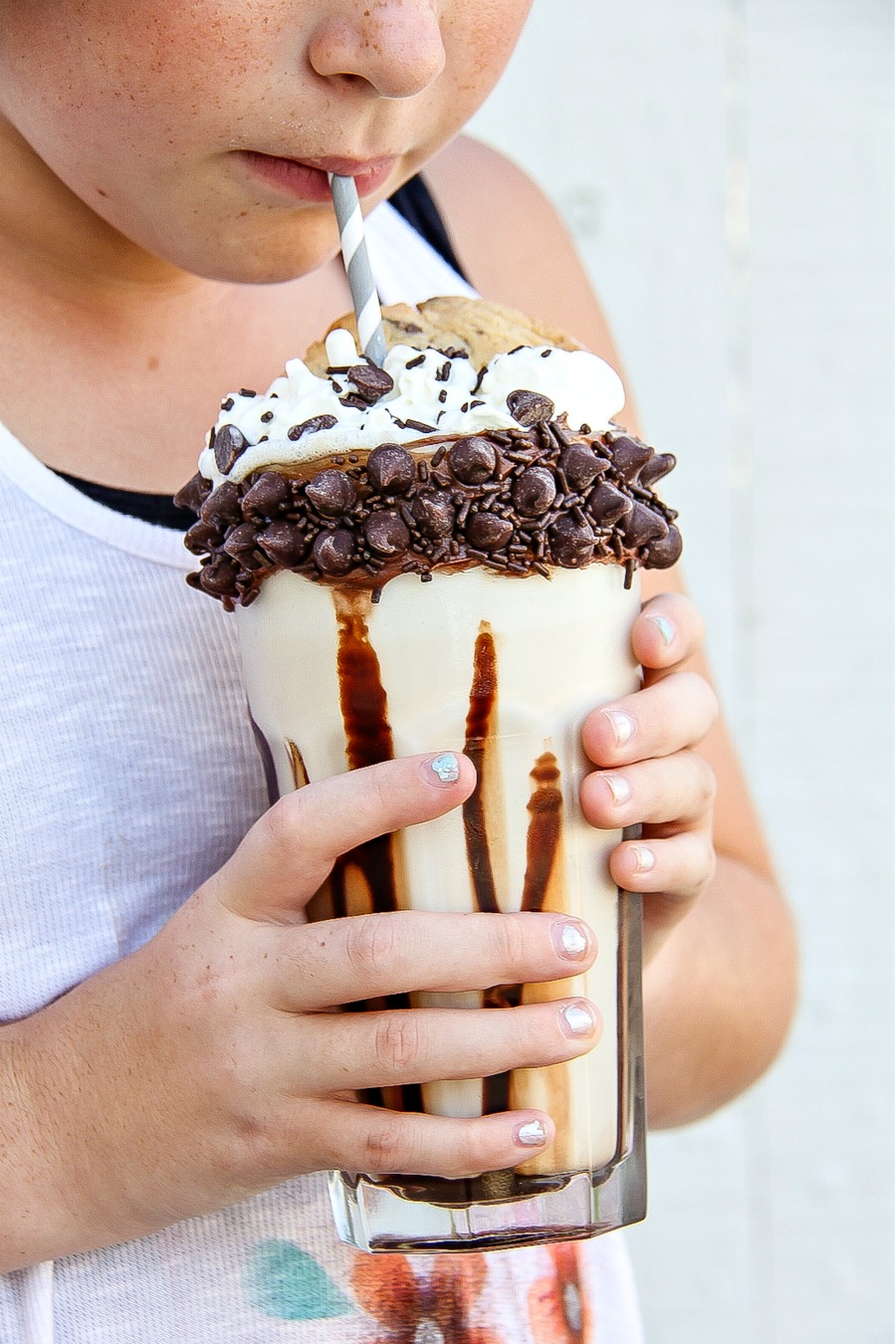 A girl drinking a chocolate chip cookie over-the-top milkshake