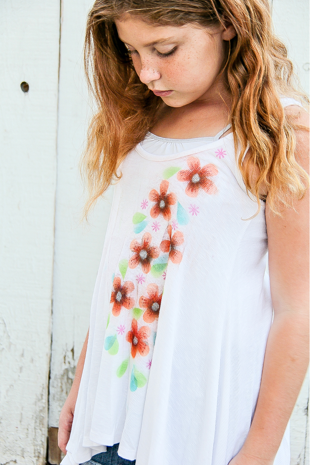 a girl wearing a white tank that has airbrush flowers on it