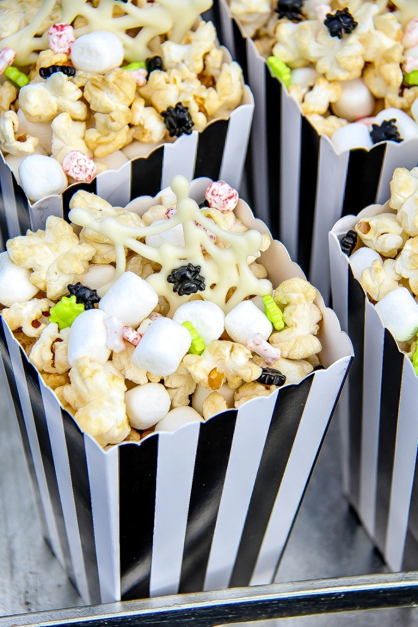 Halloween popcorn box filled with kettle corn, marshmallows, spiders, and white chocolate spider webs