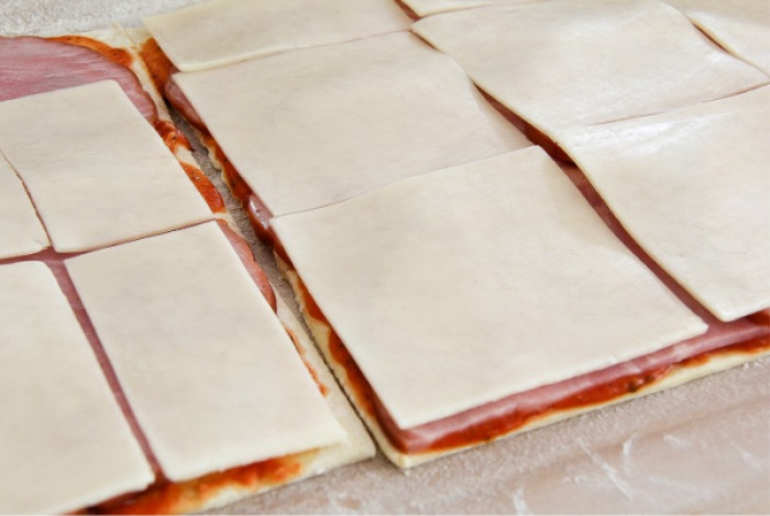 puff pastry topped with pizza sauce, ham slices, and cheese slices