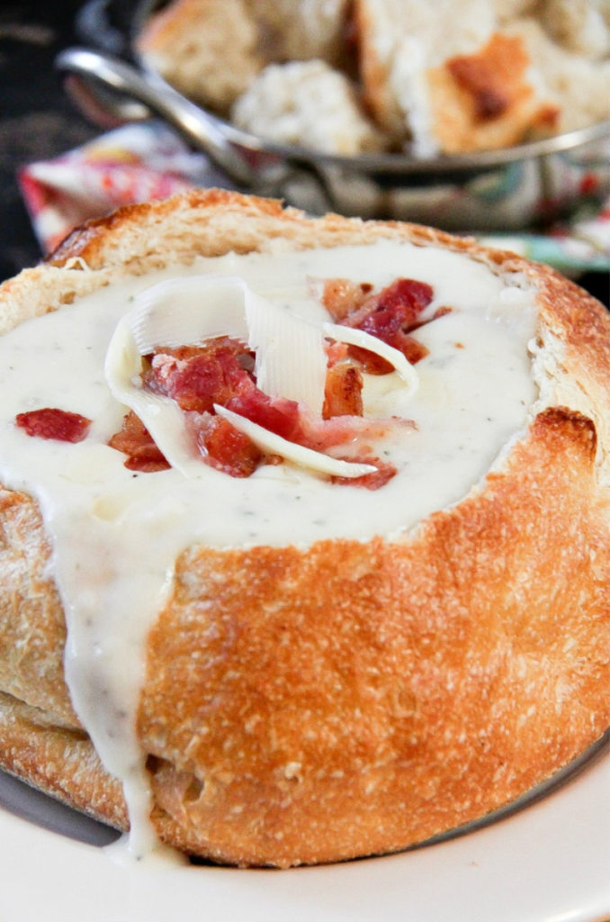 potato soup in a bread bowl with bacon pieces on top