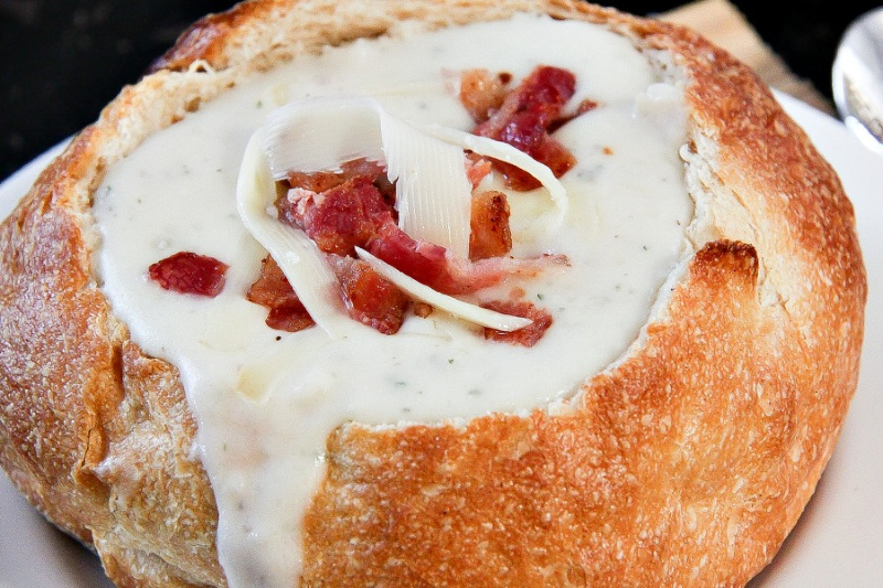 creamy potato soup topped with bacon and cheese in a bread bowl
