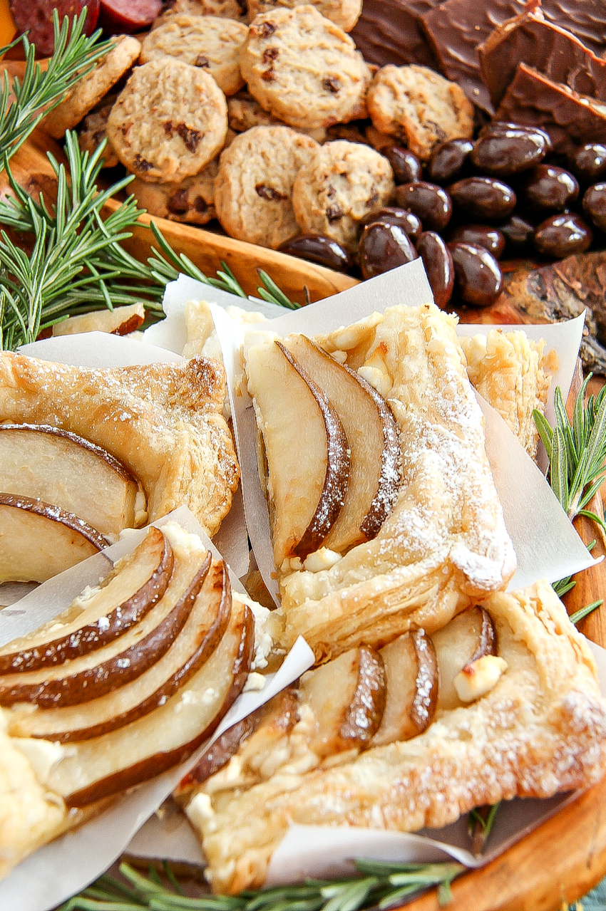 a pear tart with assorted sweet chocolates and cookies on a holiday grazing platter