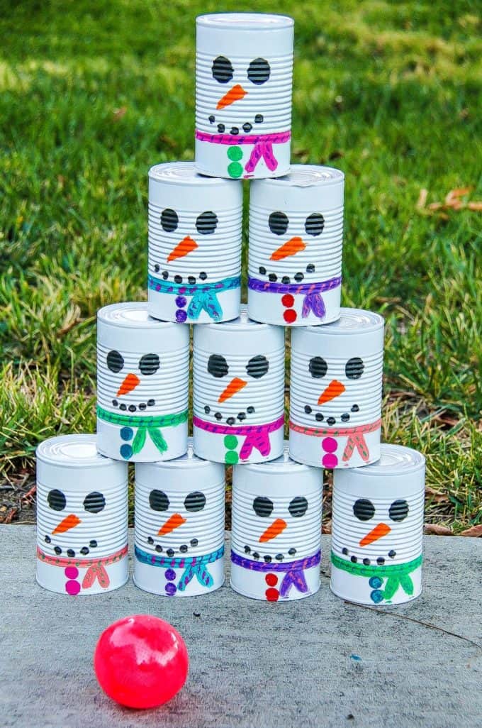 empty tin cans painted to look like a snowman for a tin can toss game with a ball