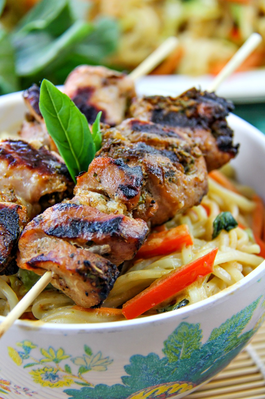 marinated pork skewers on top of a spicy noodle salad