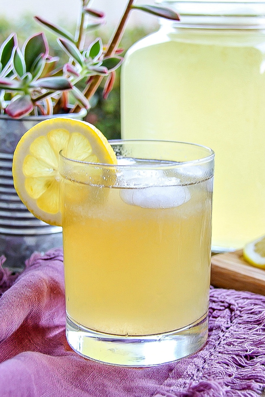 a cocktail with bourbon, lemonade, and thyme in a glass garnished with a lemon slice